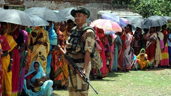 জনসমাগমে একজন সৈনিক অস্ত্র হাতে, বৃষ্টি থেকে রক্ষা পেতে ছাতা ব্যবহার করছে।. Channel i News - চ্যানেল আই নিউজ