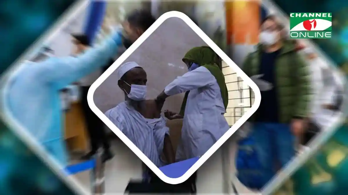 একজন ব্যক্তি করোনাভাইরাস টিকা নিচ্ছেন, স্বাস্থ্যকর্মী পাশে দাঁড়িয়ে. Channel i News - চ্যানেল আই নিউজ