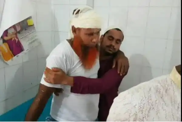 আহত ব্যক্তি হাসপাতালে চিকিৎসাধীন, পাশে অন্য ব্যক্তি সমর্থন দিচ্ছেন. Channel i News - চ্যানেল আই নিউজ