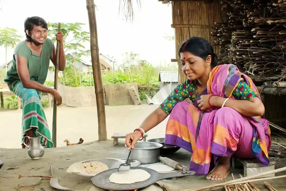 একজন নারী রান্না করছেন, পাশে একজন শিশু হাসছে. Channel i News - চ্যানেল আই নিউজ