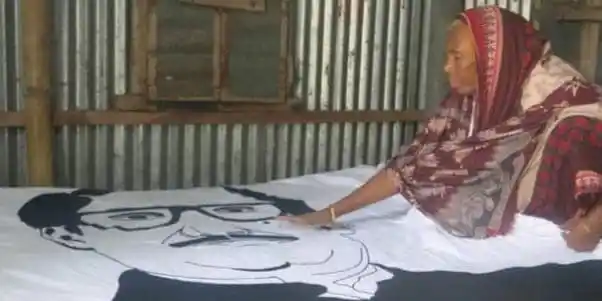 বৃদ্ধা নারী একটি পত্রিকা বা ছবি দেখছেন, ঘরের ভিতরে।. Channel i News - চ্যানেল আই নিউজ