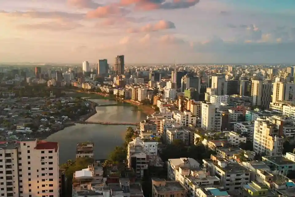 ঢাকার skyline with river and high-rise buildings at sunset. Channel i News - চ্যানেল আই নিউজ