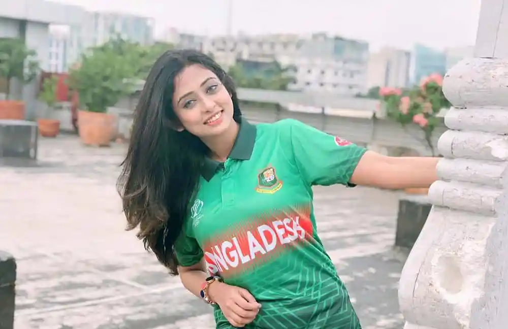 বাংলাদেশের পতাকাসহ যুবতী নারী রঙিন জার্সি পরে ছাদে হাসিমুখে ছবি. Channel i News - চ্যানেল আই নিউজ