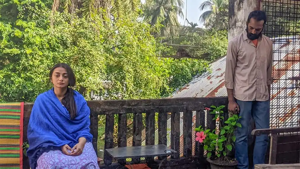 একজন নারী বসে আছেন, অন্যজন ফুলের গাছে নজর দিচ্ছেন. Channel i News - চ্যানেল আই নিউজ
