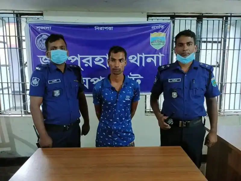নিরাপত্তা বাহিনীর দুই সদস্যের সঙ্গে একজন ব্যক্তি দাঁড়িয়ে আছেন. Channel i News - চ্যানেল আই নিউজ