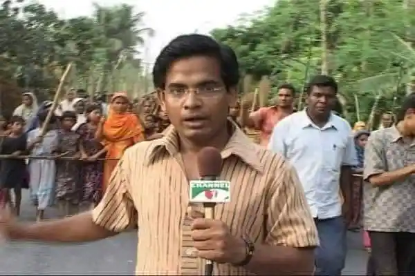 বাংলাদেশের একজন সাংবাদিক রিপোর্ট করছেন, পেছনে জনতা ও প্রকৃতি দৃশ্য।. Channel i News - চ্যানেল আই নিউজ