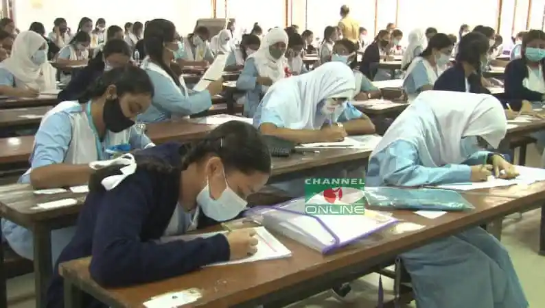 Students taking an exam in a classroom, wearing masks for safety. Channel i News - চ্যানেল আই নিউজ
