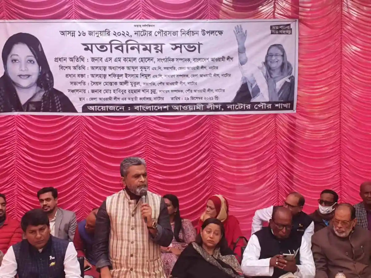 নির্বাচনী সভায় বক্তা ও উপস্থিত দর্শক, পটভূমিতে বড় ব্যানার. Channel i News - চ্যানেল আই নিউজ