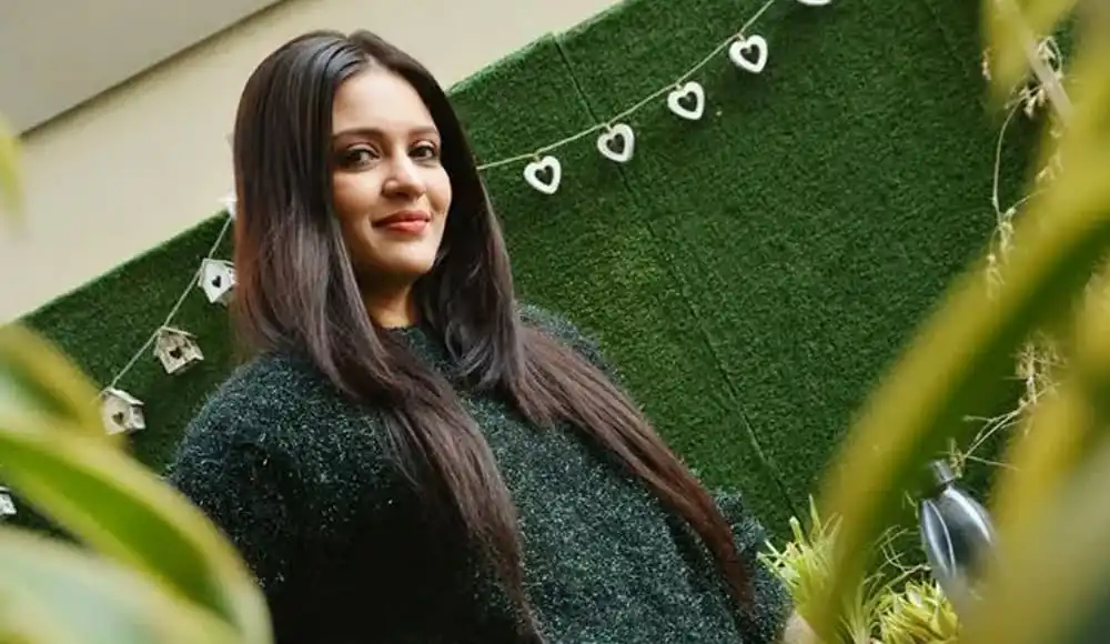 প্রিয়াঙ্কা হাসিমুখে দাঁড়িয়ে আছেন, পেছনে সবুজ দেয়াল ও হালকা আলোর ঝলকানি. Channel i News - চ্যানেল আই নিউজ