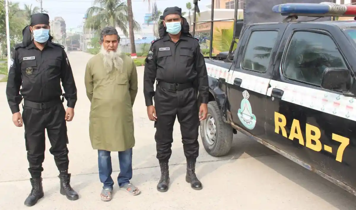 নিরাপত্তা কর্মীরা একজন ব্যক্তিকে আটক করেছে, পাশে র‍্যাবের গাড়ি দাঁড়িয়ে।. Channel i News - চ্যানেল আই নিউজ