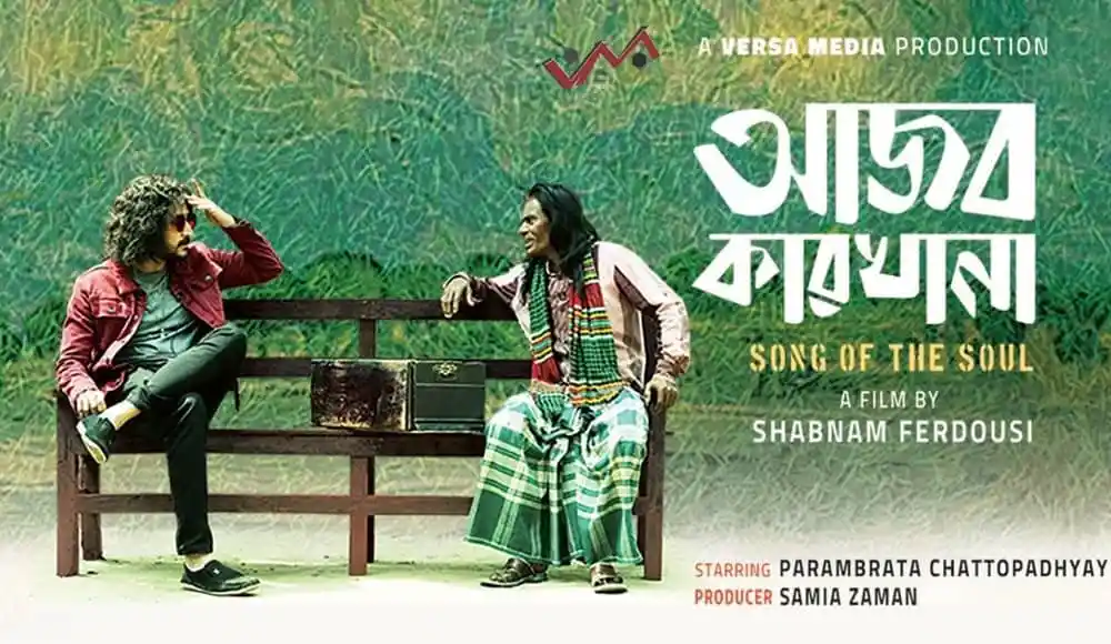 আজব কারখানা সিনেমার পোস্টার যেখানে দুই অভিনেতা গল্পের দৃশ্যে বসে আছেন. Channel i News - চ্যানেল আই নিউজ