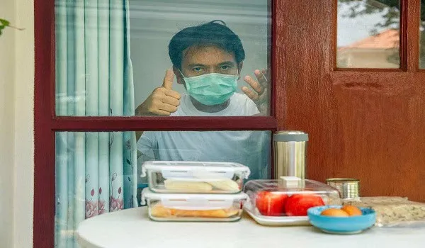 Boy wearing face mask looking through window with food on table. Channel i News - চ্যানেল আই নিউজ
