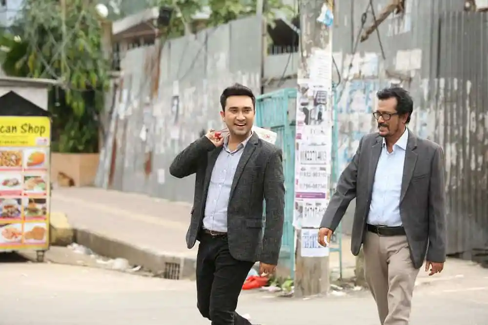দুজন পুরুষ রাস্তার পাশে হাঁটছেন, হাসছেন ও কথাবার্তা বলছেন. Channel i News - চ্যানেল আই নিউজ