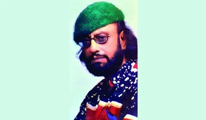 গীতিকার কাওসার আহমেদ চৌধুরীর ছবি, কালো চুল, গা dark, গাঢ় sunglasses, পেছনে হালকা সবুজ ব্যাকগ্রাউন্ড. Channel i News - চ্যানেল আই নিউজ