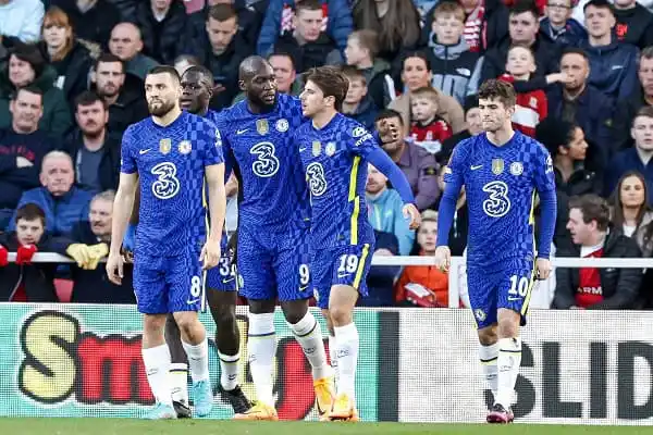 Chelsea players walking on the field during a match with fans in the background. Channel i News - চ্যানেল আই নিউজ