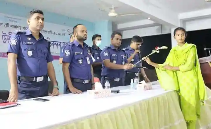 পুলিশ সদস্যরা এক অনুষ্ঠানে ফুল দিয়ে একজন মহিলাকে স্বাগত জানাচ্ছেন।. Channel i News - চ্যানেল আই নিউজ