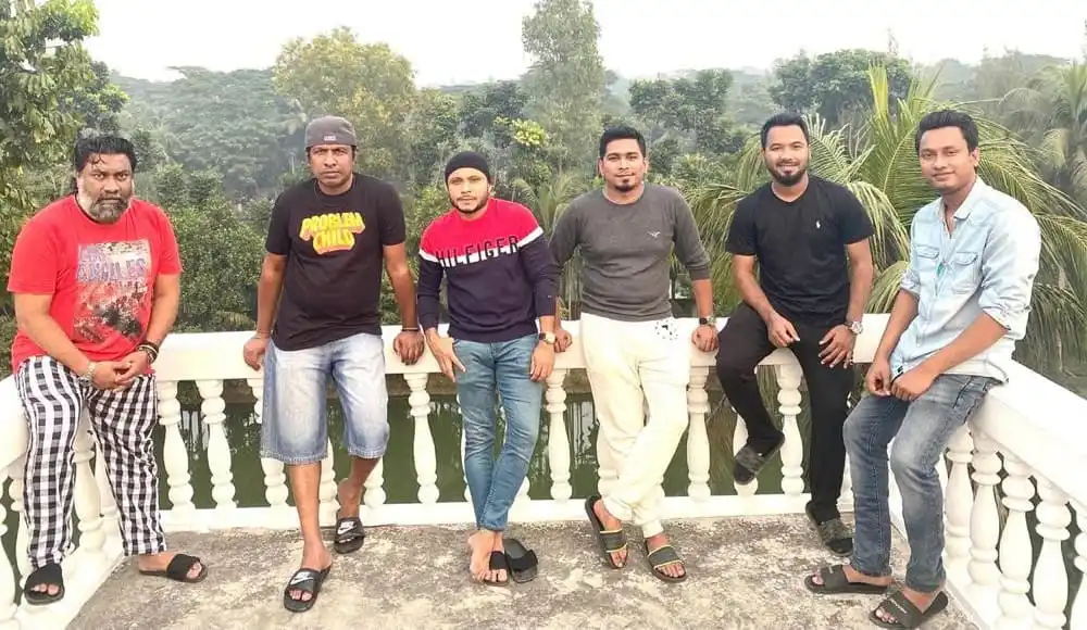 ছয়জন যুবক একসঙ্গে ছবি তুলছেন, পেছনে সবুজ গাছপালা ও আকাশ দেখা যাচ্ছে. Channel i News - চ্যানেল আই নিউজ