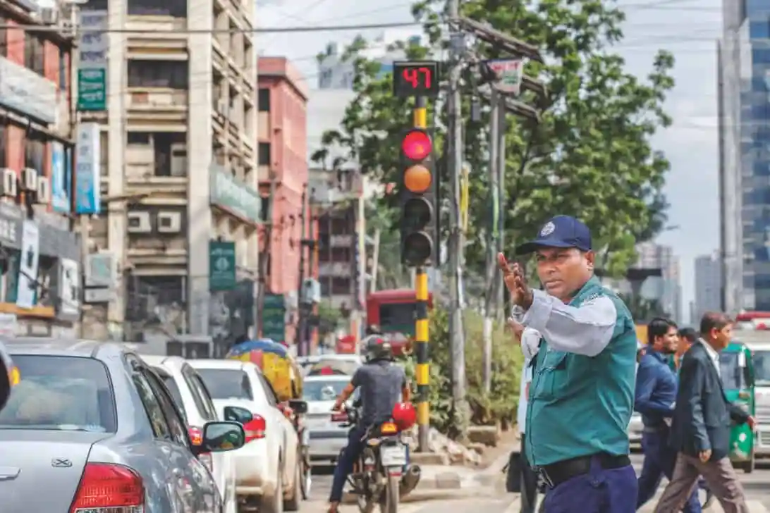 Traffic police officer managing traffic at busy city intersection in Bangladesh. Channel i News - চ্যানেল আই নিউজ