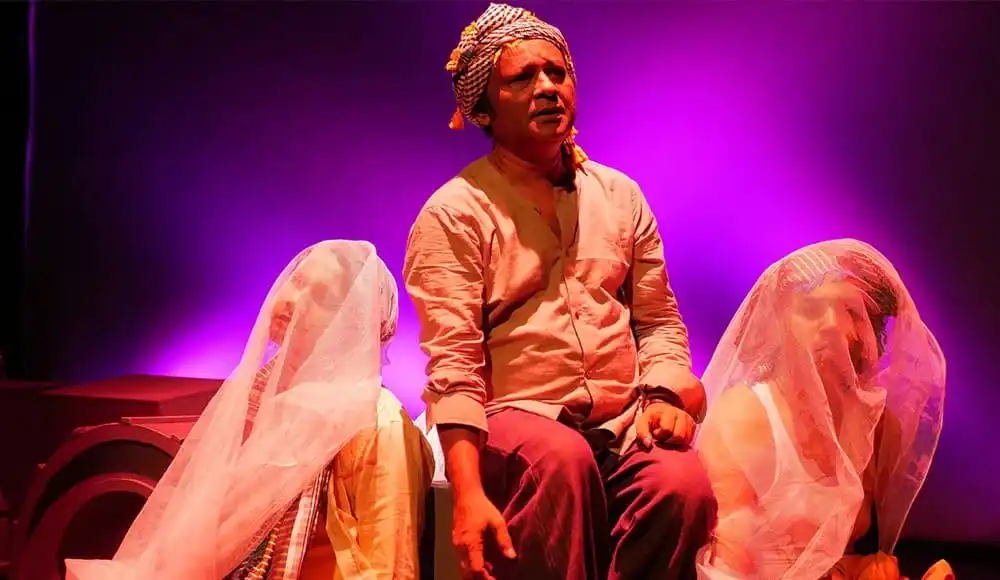নাট্যশিল্পীরা মঞ্চে পারফর্ম করছেন, উজ্জ্বল লাল ও গোলাপি আলোতে আলোচিত. Channel i News - চ্যানেল আই নিউজ