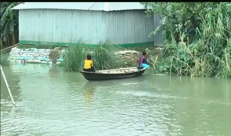 নদীতে প্লাবিত এলাকা, দুই ব্যক্তি নৌকায় করে চলাচল করছে. Channel i News - চ্যানেল আই নিউজ
