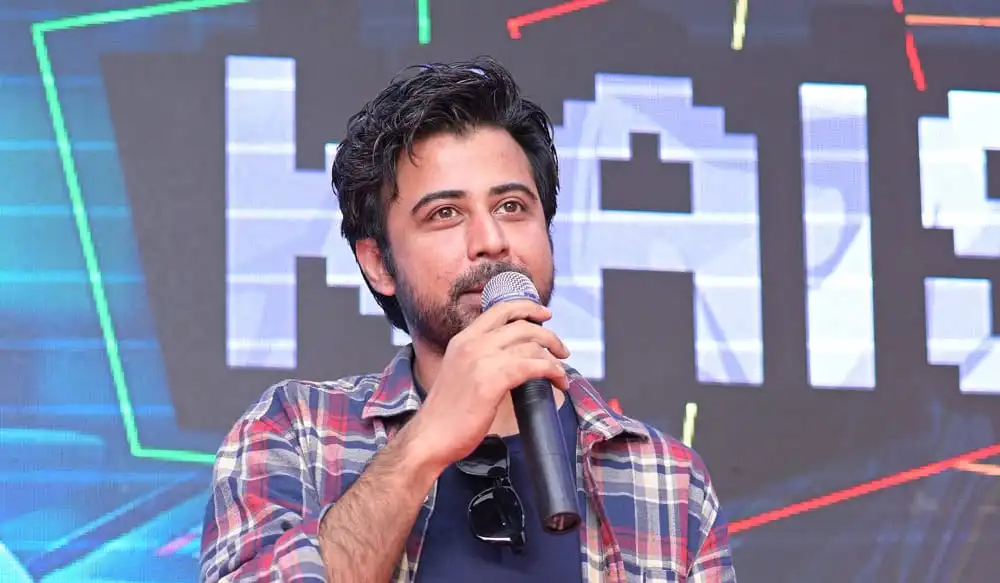 বাংলাদেশি যুবক বক্তৃতা দিচ্ছেন, পেছনে ডিজিটাল লাইটিং ও ব্যাকড্রপ. Channel i News - চ্যানেল আই নিউজ