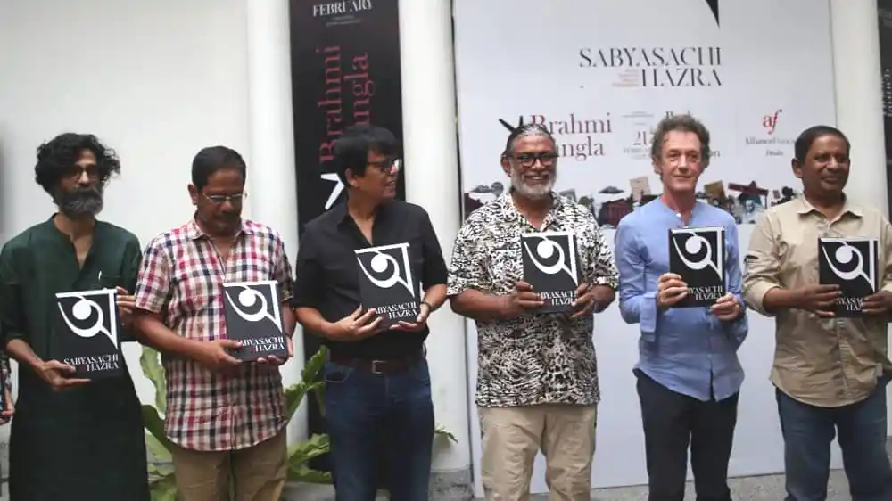প্রদর্শনীতে অংশগ্রহণকারী শিল্পীরা বই হাতে দাঁড়িয়ে আছেন. Channel i News - চ্যানেল আই নিউজ
