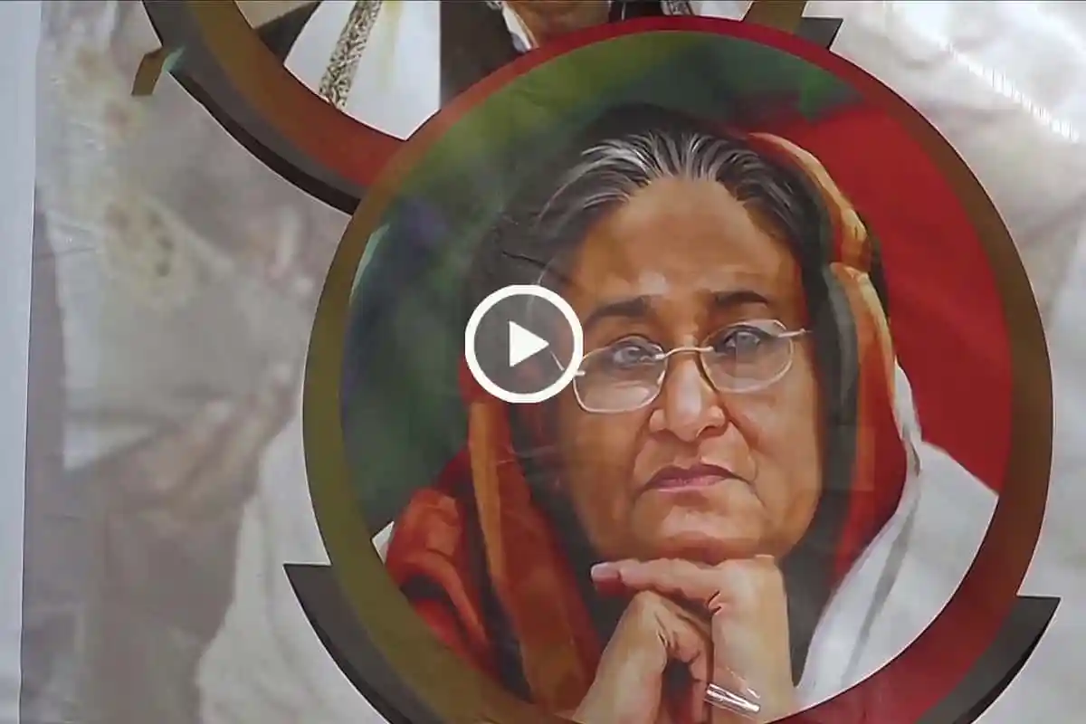 শেখ হাসিনা ভাবুক মুখ, চোখে গভীর দৃষ্টি, পেছনে লাল ও সাদা ব্যাকগ্রাউন্ড. Channel i News - চ্যানেল আই নিউজ