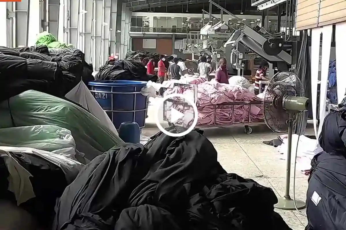 Bangladeshi garment factory workers working amid fabric and machinery. Channel i News - চ্যানেল আই নিউজ