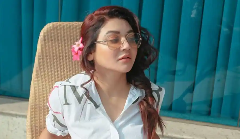 একজন তরুণী সূর্যরশ্মির মধ্যে বসে আছেন, চুলে ফুল দিয়ে সাজানো. Channel i News - চ্যানেল আই নিউজ