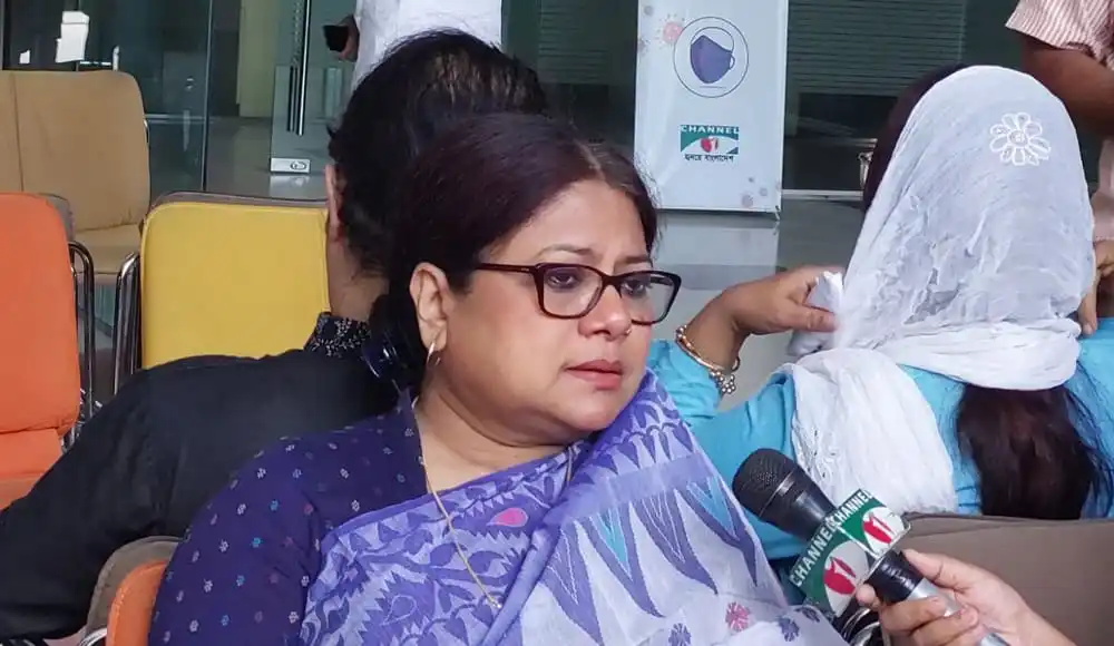 কনকচাঁপা এক সংবাদ সম্মেলনে কথা বলছেন, পেছনে অন্যরা বসে আছেন. Channel i News - চ্যানেল আই নিউজ