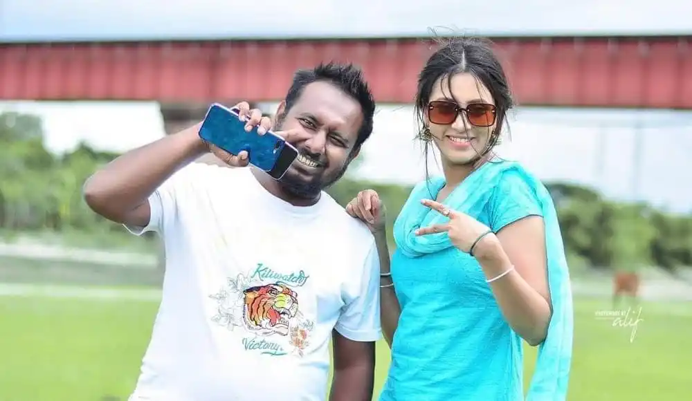 একজন পুরুষ ও একজন মহিলা হাসি ও সেলফি তুলছেন. Channel i News - চ্যানেল আই নিউজ