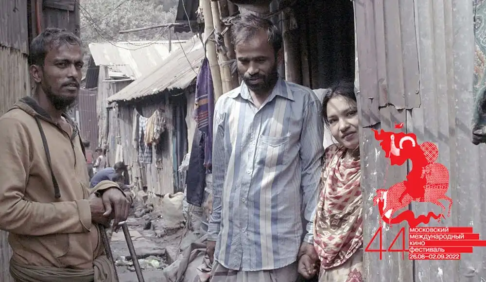 তিনজন ব্যক্তি দারিদ্র্যপূর্ণ এলাকায় দাঁড়িয়ে, একটি ছবি যা বাংলাদেশের জীবনযাত্রার চিত্র দেখায়. Channel i News - চ্যানেল আই নিউজ