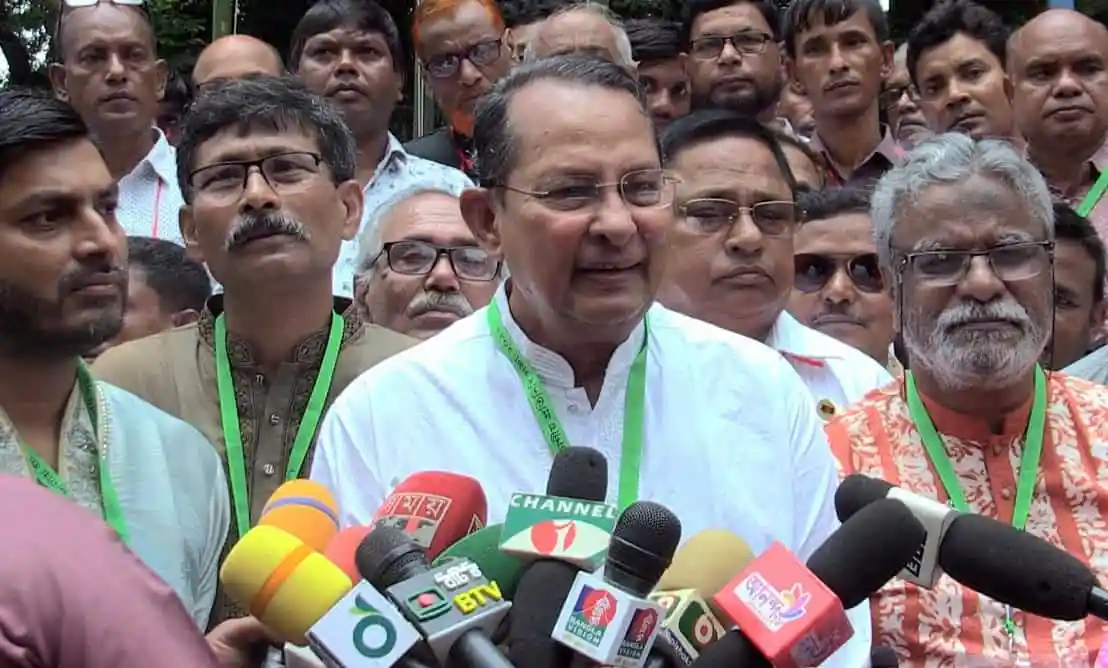 Inu speaking to media surrounded by supporters and journalists. Channel i News - চ্যানেল আই নিউজ