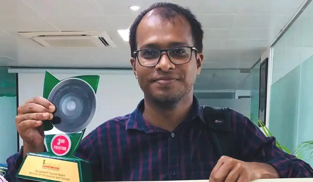 শামসুল হক রিপন পুরস্কার গ্রহণ করছেন, হাসিমুখে ছবি. Channel i News - চ্যানেল আই নিউজ