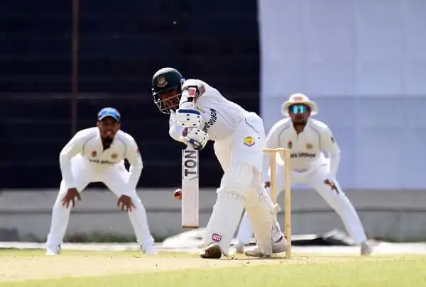 ক্রিকেট খেলোয়াড় ব্যাটিং করছে, পেছনে ফিল্ডাররা প্রস্তুত. Channel i News - চ্যানেল আই নিউজ