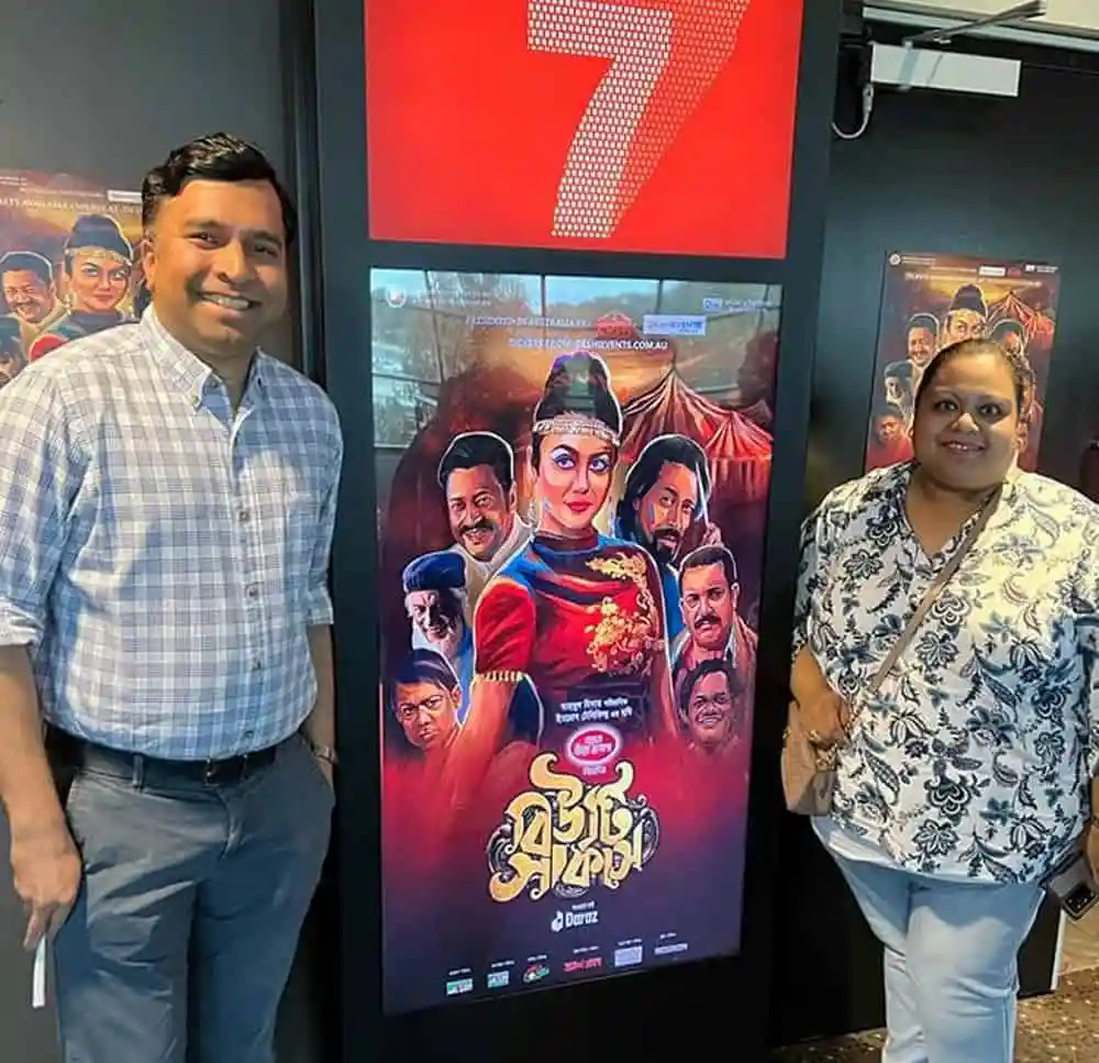 দুটি মানুষ ছবি পাশে দাঁড়িয়ে, বিউটি সার্কাসের পোস্টার দেখছেন. Channel i News - চ্যানেল আই নিউজ