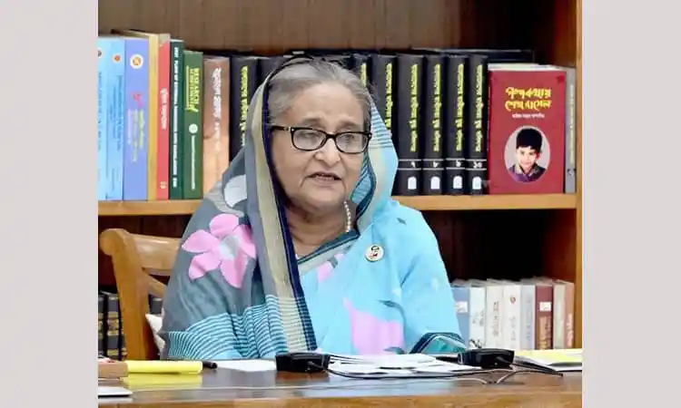 প্রধানমন্ত্রী শেখ হাসিনা বইয়ের সামনে বসে আলোচনা করছেন।. Channel i News - চ্যানেল আই নিউজ