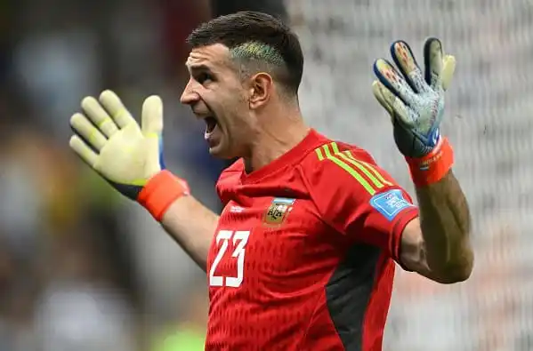 Goalkeeper in red jersey with gloves, shouting during a match. Channel i News - চ্যানেল আই নিউজ