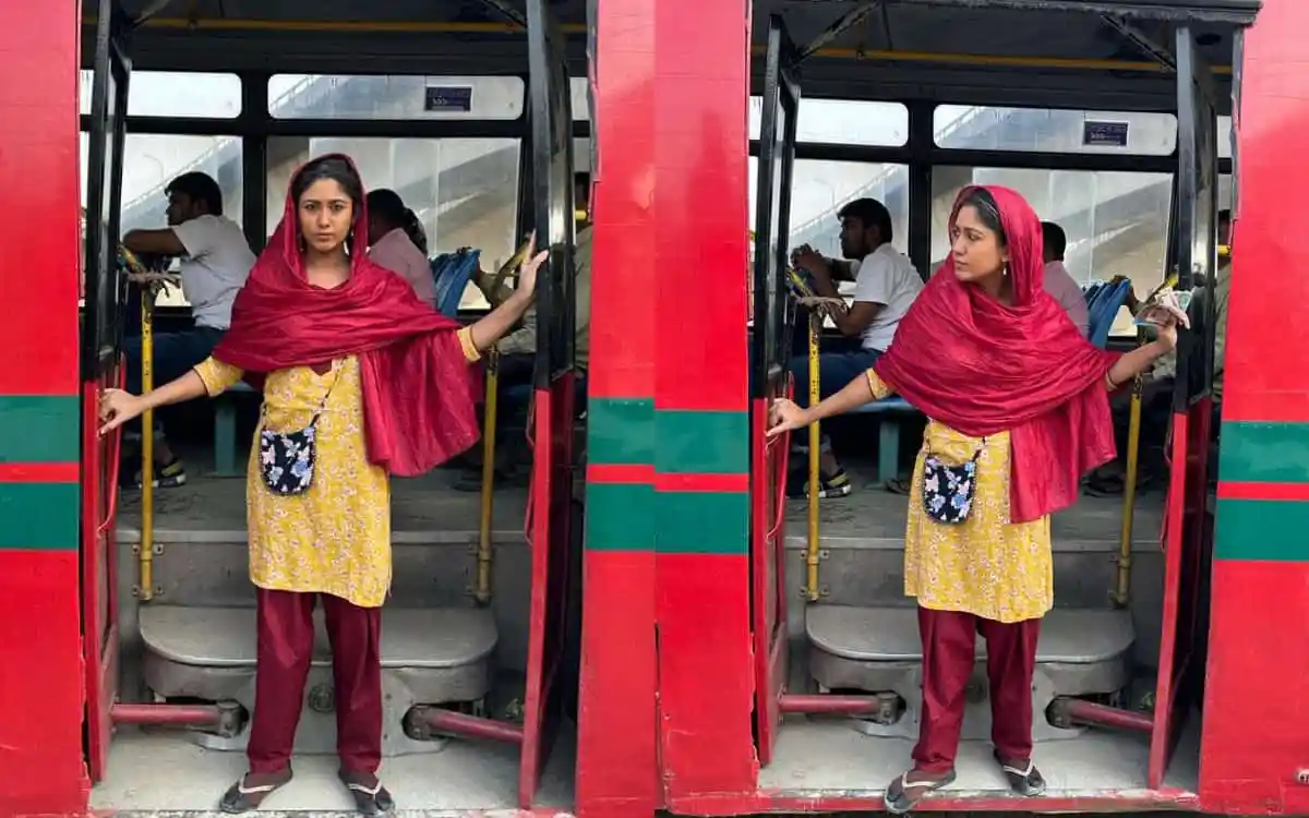 A woman in traditional Bengali attire standing at a bus door in Bangladesh. Channel i News - চ্যানেল আই নিউজ