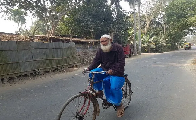 82-year-old man cycling on a rural road in Bangladesh. Channel i News - চ্যানেল আই নিউজ