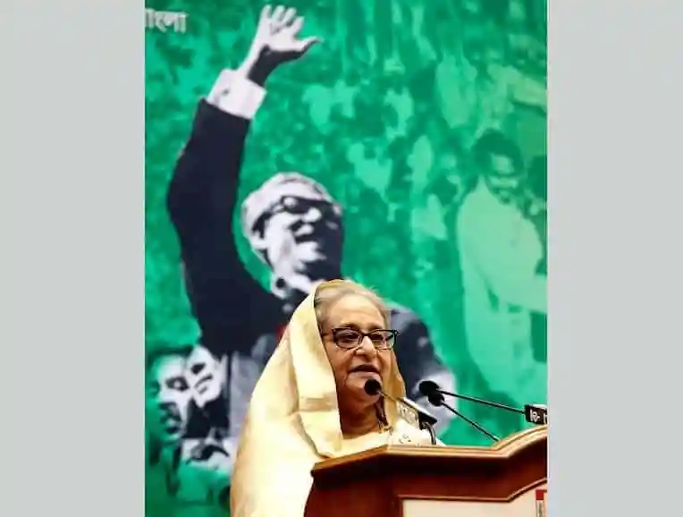শেখ হাসিনা ভাষণ দিচ্ছেন, পেছনে নেতাদের ছবি. Channel i News - চ্যানেল আই নিউজ