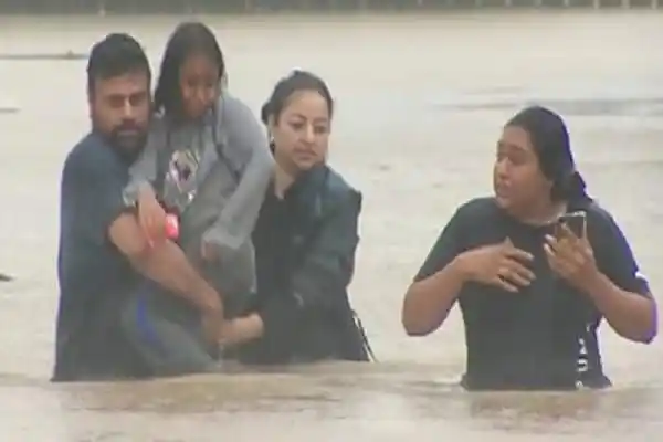 বন্যার পানিতে মানুষজন, একজন শিশু সহ পরিবারের সদস্যরা. Channel i News - চ্যানেল আই নিউজ