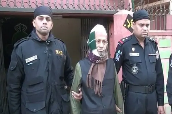 পলাতক আসামীকে গ্রেপ্তার করে পুলিশ, দুই পুলিশ সদস্য পাশে দাঁড়িয়ে. Channel i News - চ্যানেল আই নিউজ