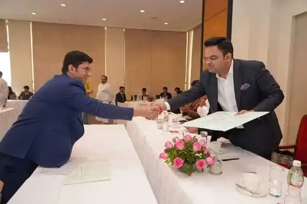 দুই ব্যক্তি হাত মিলাচ্ছেন, একটি সম্মেলন কক্ষে সাক্ষাৎ. Channel i News - চ্যানেল আই নিউজ