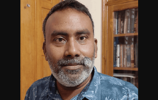 প্রফুল্ল ব্যক্তি একটি বইয়ের সামনে দাঁড়িয়ে আছেন. Channel i News - চ্যানেল আই নিউজ