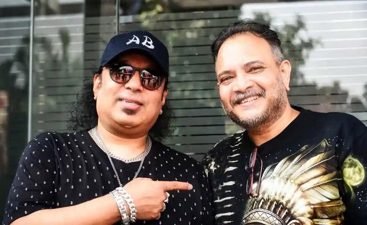 দুই ব্যক্তি হাসিমুখে ছবি তুলেছেন, একজন পলক ও ক্যাপ পরা, অন্যজন গ্লাস পরা. Channel i News - চ্যানেল আই নিউজ