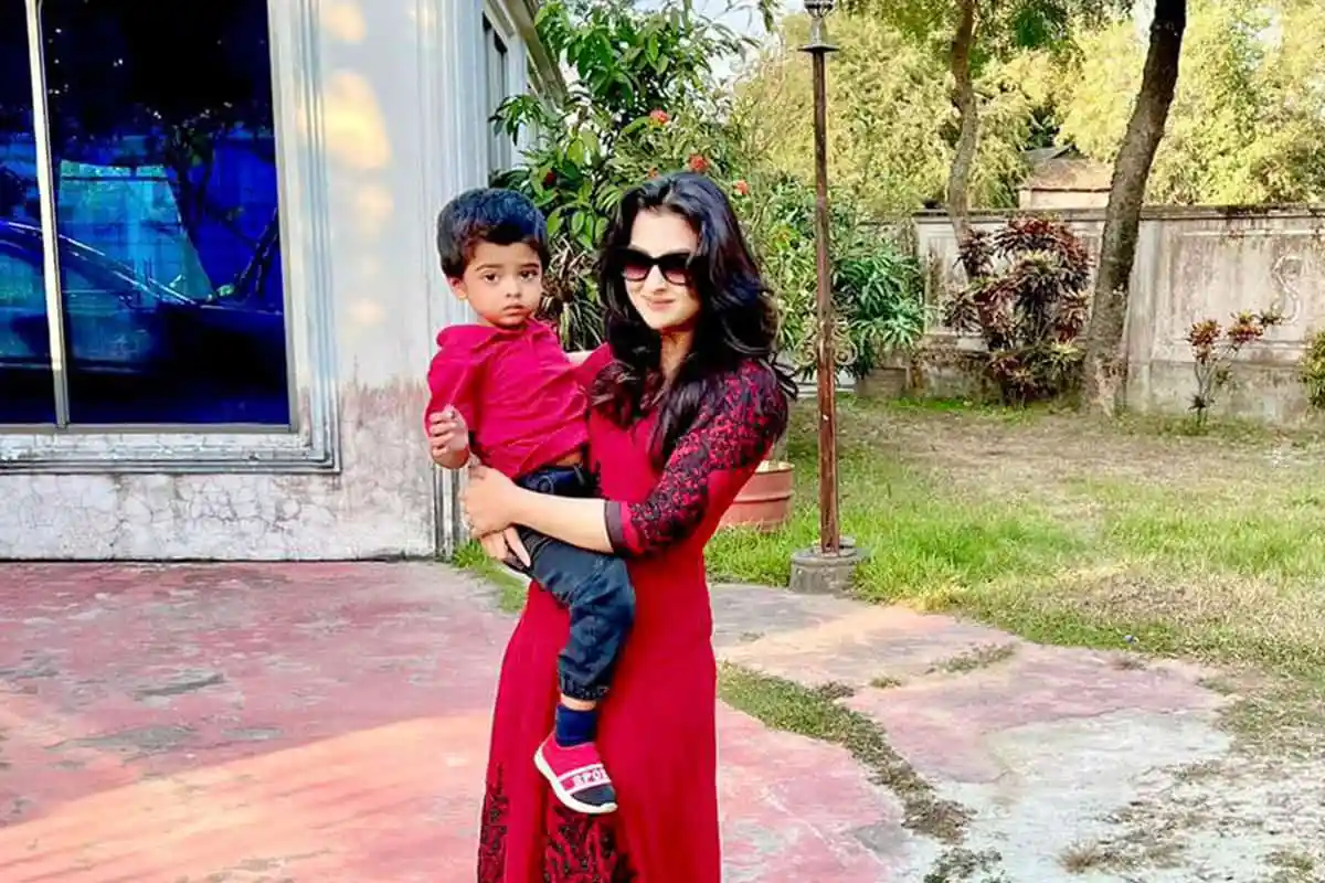 একজন নারী তার সন্তানকে নিয়ে খোলা আঙিনায় দাঁড়িয়ে আছেন।. Channel i News - চ্যানেল আই নিউজ