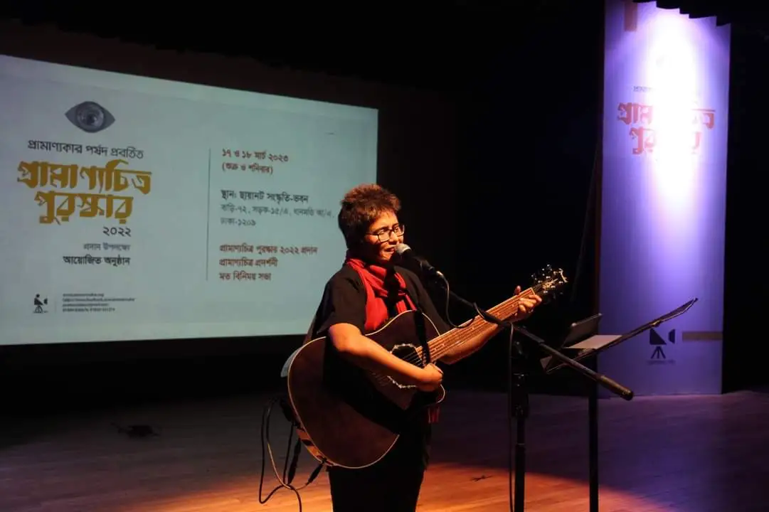 একজন শিল্পী গিটার বাজাচ্ছেন এবং মঞ্চে পারফর্ম করছেন. Channel i News - চ্যানেল আই নিউজ