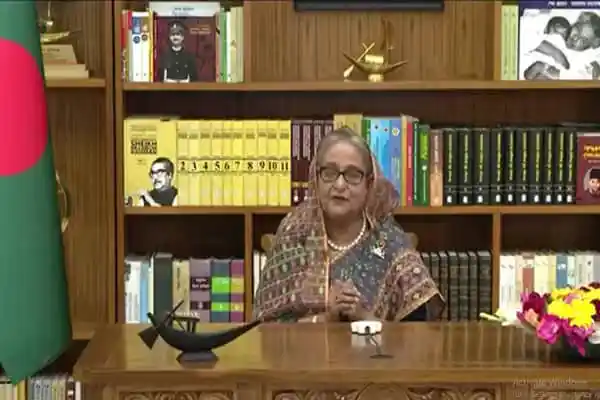 প্রধানমন্ত্রী জাতীয় সংসদে ভাষণ দিচ্ছেন, পেছনে বইয়ের শেলফ ও বাংলাদেশ পতাকা. Channel i News - চ্যানেল আই নিউজ