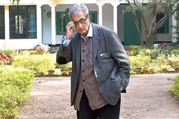 অমর্ত্য সেন বাড়ির বাইরে দাঁড়িয়ে স্মার্টফোনে কথা বলছেন. Channel i News - চ্যানেল আই নিউজ